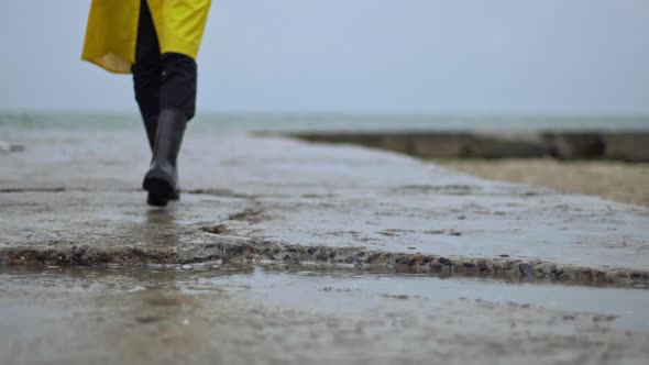 Person Walking Toward Pier Rain Boots Steps in Puddle Closeup alt