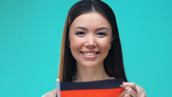 Woman Covering Mouth by German Flag, Foreign University Education, Migration alt