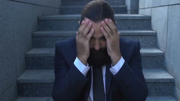 Bankrupt Businessman Rubbing Temples in Despair, Depressed After Dismissal