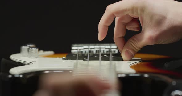 Close up of fingers strumming an electric guitar alt
