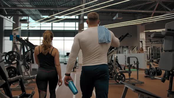Couple of Athletes Going Through the Gym to the Exercise Machines in Slow Motion alt