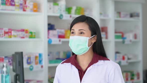 Woman pharmacist wearing medical protective face mask using thermometer to check temperature