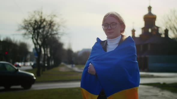 Portrait of a Joyful Ukrainian Woman Holding a Ukrainian Flag and a Sign alt