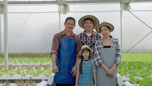 portrait of an Asian organic vegetable farmer family is standing and smiling confident in the qualit