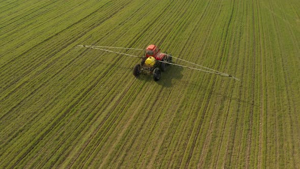 Farmer on a Sprayer with Wide Cantilevers Sprays Winter Crop Seedlings with Chemicals alt