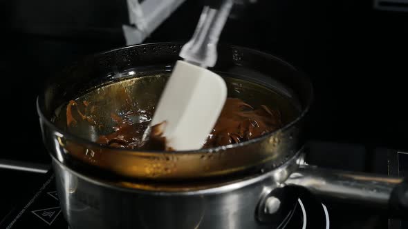 Silicone Cooking Spatula Mixes the Melted Chocolate in a Glass Bowl to Steam