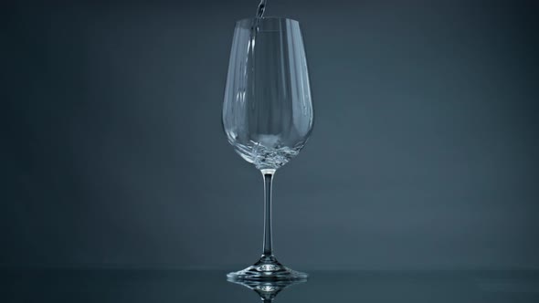 Water Pouring Wine Glass at Dark Background Closeup alt