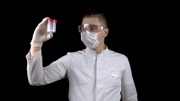 A Young Man Doctor Is Checking Sperm Tests. A Man Examines a Test Jar Containing Semen on a Black alt