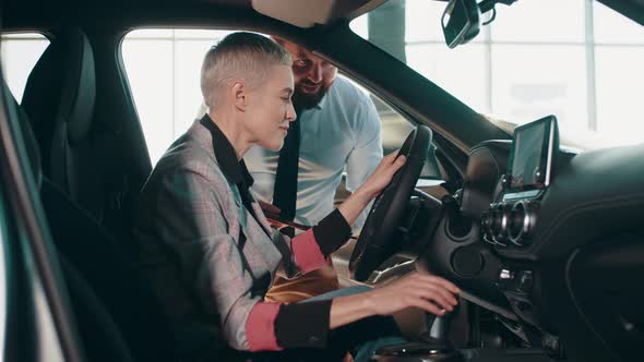 Closeup of Happy Female Testing Buying Car From Inside During Visit Auto alt