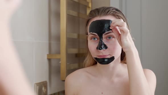 Beautiful Woman Removing Elastic Black Face Mask From Her Face alt