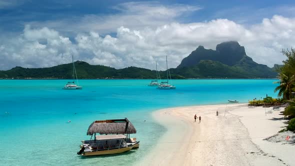 Drone shot of Bora Bora from a private Motu. perfect blue ocean with a few catamaran anchor in front alt