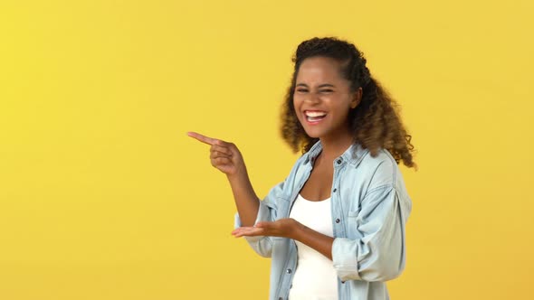 African American woman acting surprised and amazed while pointing with open hands to copy space