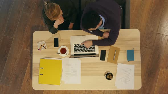 Manager and His Pretty Young Colleague Sitting in Office and Working on Business Presentation