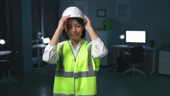 Portrait of AfricanAmerican Woman Engineer in Safety Vest Look at Camera and Put on Helmet alt