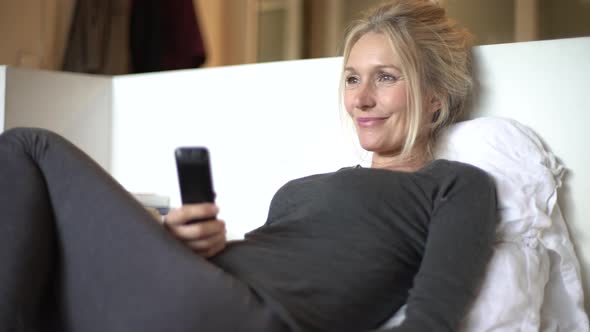 Mature woman laughing while watching TV