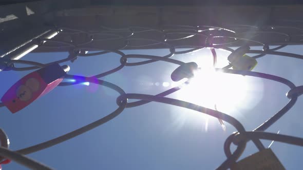 A closeup of a metal mesh fence with symbolic locks on it alt