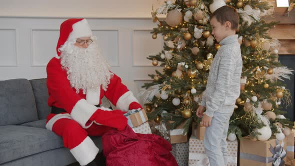 Santa Claus Giving Gift Box To Little Boy Congratulating Kid on Christmas at Home alt