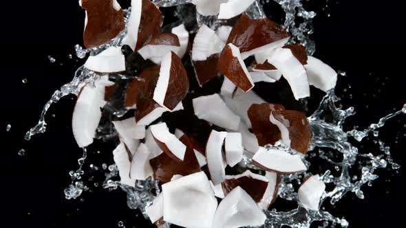 Super Slow Motion Shot of Rotating Exploded Coconut Cuts and Splashing Water on Black at 1000Fps alt