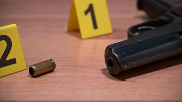 on the Crime Scene, on the Floor, Lay a Pistol and Shell Casing Marked with Photo Markers alt