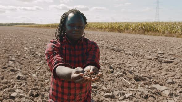African Farmer Holding Soil in His Hands. Medium Shot on the Farm alt