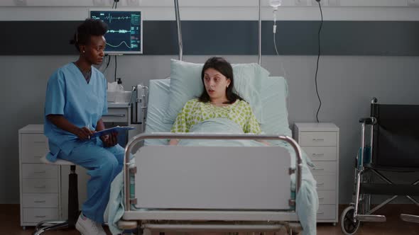 Sick Woman Adult Resting in Bed While Black Nurse Analyzing Disease Expertise alt