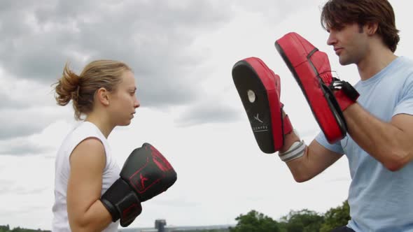 Male and female box training in park alt