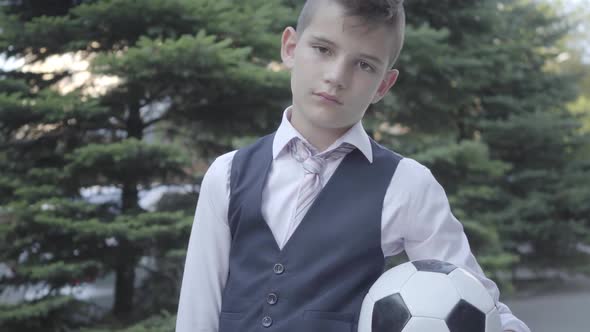 Portrait Cute Well-dressed Boy Standing on the Street Holding the Soccer Ball and Purse alt