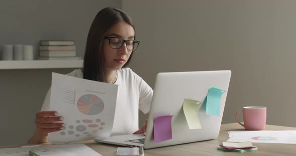 A Girl with Glasses Is Working on a Laptop and Looking at the Diagram alt