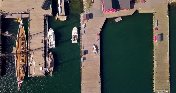 Aerial footage of sailboats and tall ships docked in the harbor at Lunenburg, Nova Scotia, Canada alt
