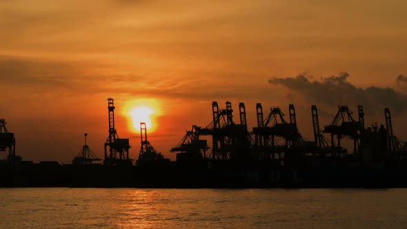 Silhouette of Cranes loading cargo to a freighter at industrial dock time lapse footage. alt