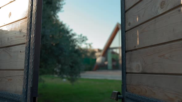 Wooden Fence Door Opens Showing Big Yard with Luxury House alt