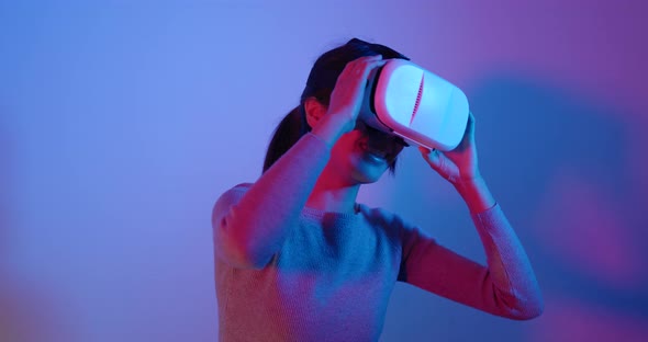 Woman looking though virtual reality device over red and blue light alt