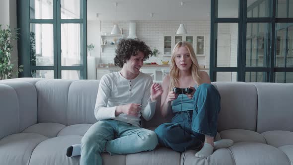 Young Blonde Woman Playing in a Console Game Against Her Partner alt