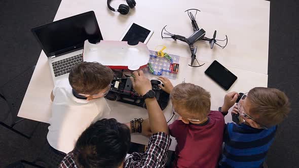 Three Schoolchildren with Teacher Trying to Repair Computer Board alt