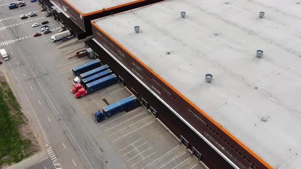 Large Warehouse with Trucks and Cars on Parking Lot alt