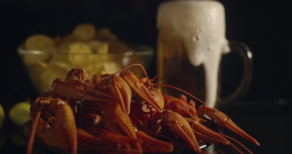 Close Up View of Lobsters with Foamy Bear Pouring in Glass and Crisp Chips on Background in Slow