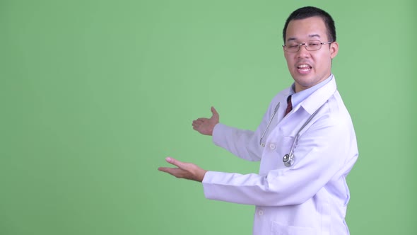 Happy Asian Man Doctor Talking While Showing To the Back alt