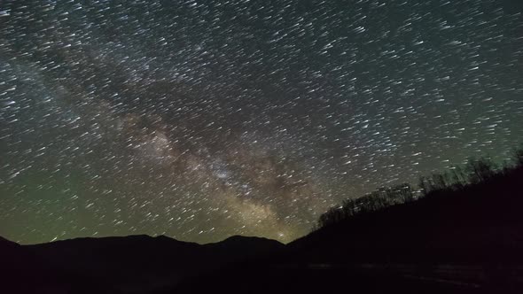 Milky way moving with trails of stars over silhouette of mountains at Osum River, Albania alt