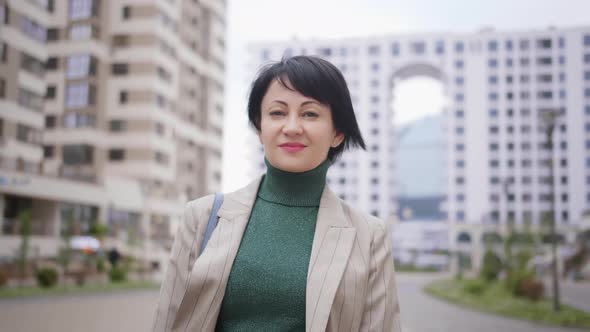 Business Brunette Woman Walking Down the Street and Smiling in the Evening alt