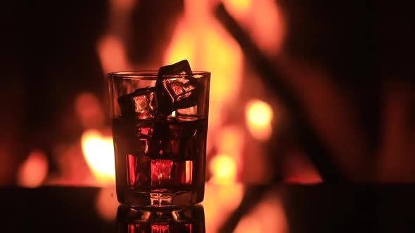 Glass of Whiskey with Ice Near the Fireplace alt