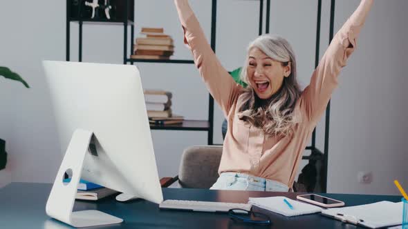 Happy Mature Middle Aged Elderly Business Woman Winner Excited By Reading Good News Looking at alt