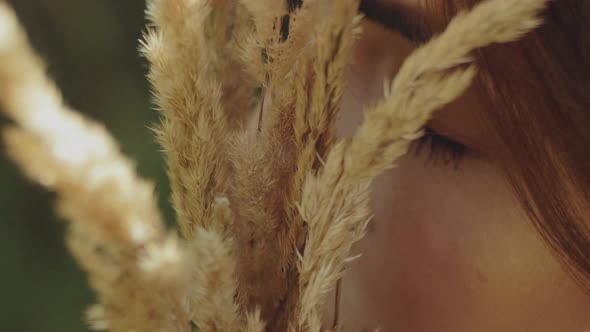 Closeup Portrait of an Attractive Woman with Closed Eyes and a Bouquet of Spikelets in Her Hands alt