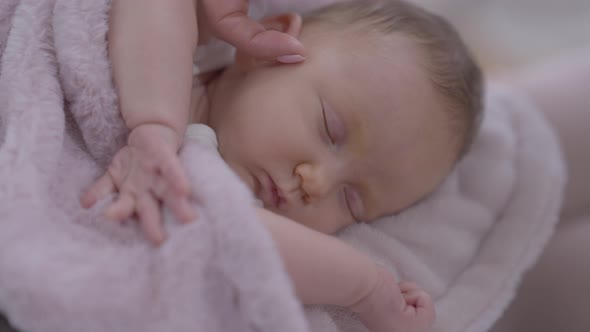 Closeup Sleeping Infant with Female Finger Caressing Cheek alt