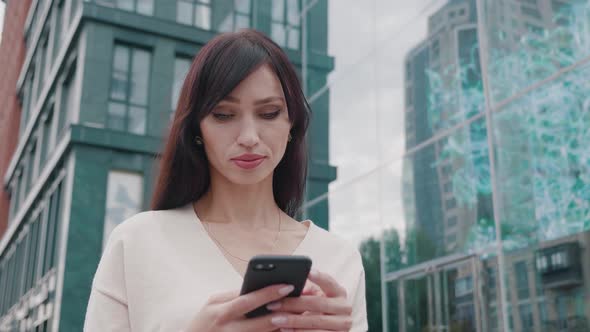 Confident Businesswoman Texting Messages on Smartphone Near Big Modern Business Center