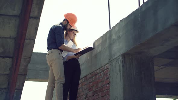 Two Architects Working On Building Model Blueprints. Engineers In Safety Helmet Construction House. alt