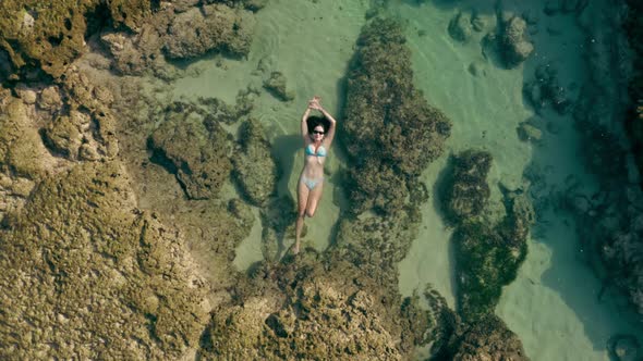 Aerial Footage of Female Person in White Bikini Laying on Natural Reef in the Ocean alt