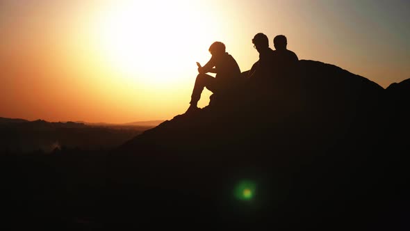 Silhouette group of people admiring the sunset on top of mountain
