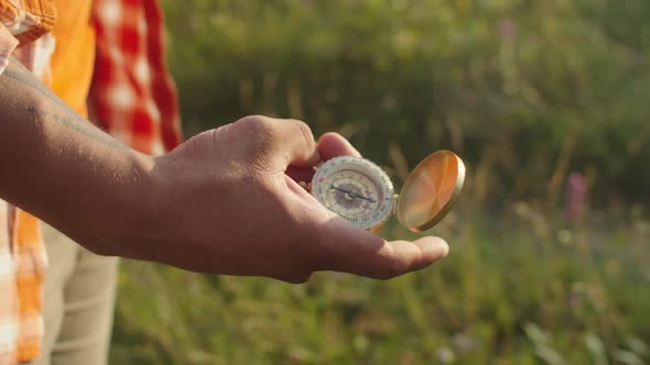 Black Male Hand Holding Magnetic Compass for Navigation Outdoors at Sunset alt