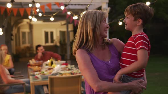 Grandmother carrying her grandson outdoors alt