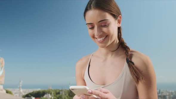 Woman Using Smartphone in City of Barcelona. Girl Sitting in Lotus Pose Outdoors alt